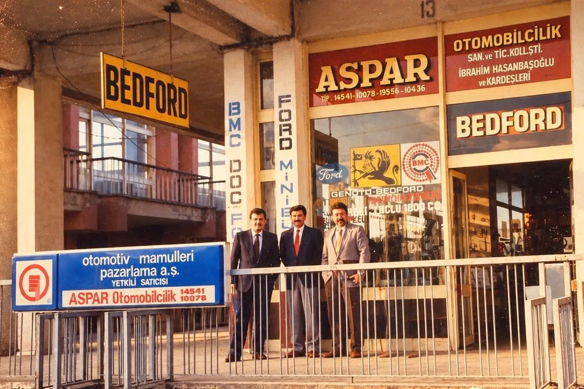 Bedford ve ASPAR tabelalı iş yerinin önünde üç kişi.